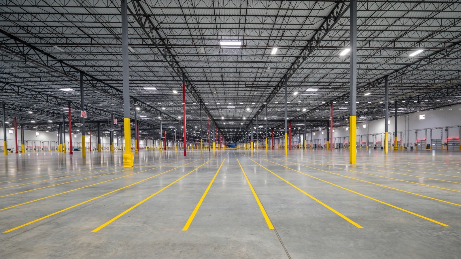 Interior of a large distribution facility with a sealed concrete floor and yellow lane striping
